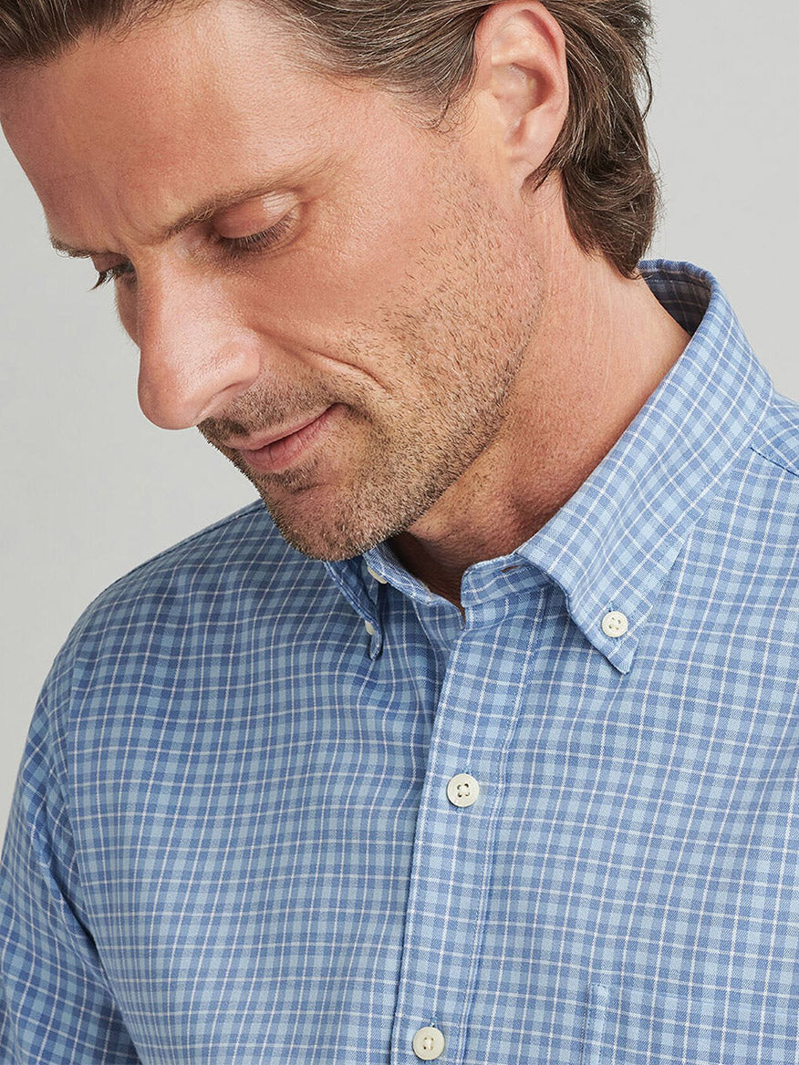 Man wearing the Peter Millar Caspian Perfect Pinpoint Cotton-Stretch Sport Shirt in Blue Freesia looking down.