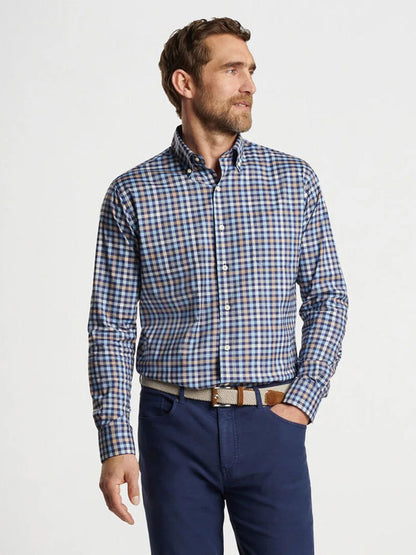 The man stands against a plain background, looking to the side, wearing a Peter Millar Chambly Crown Lite Cotton-Stretch Sport Shirt in Navy paired with navy pants.