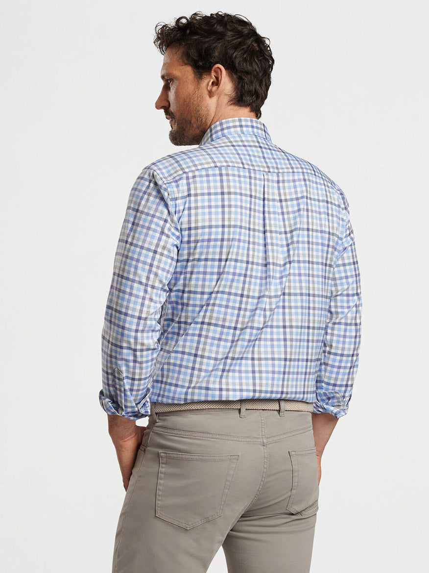 A man with dark hair is shown from the back wearing a blue and white Peter Millar Chambly Crown Lite Cotton-Stretch Sport Shirt in White and gray pants. He has his hands in his pockets.