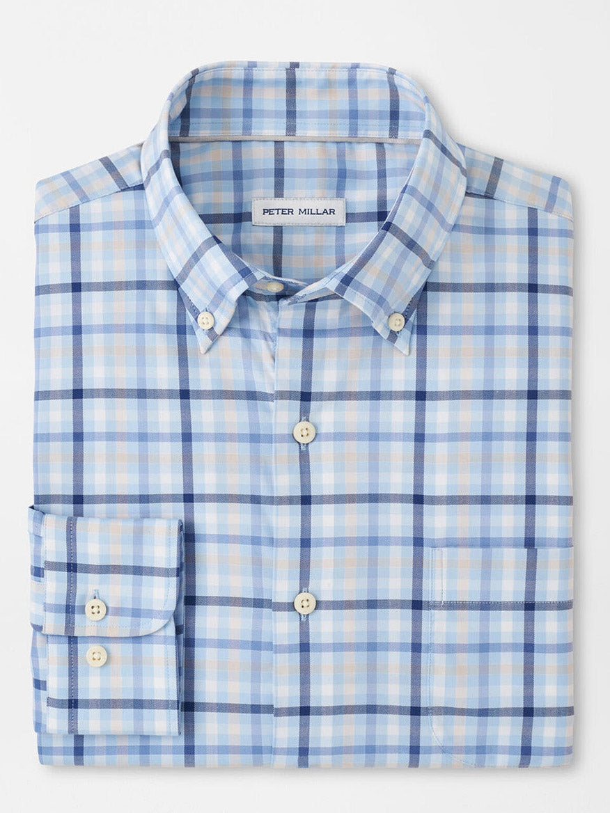 The Peter Millar Chambly Crown Lite Cotton-Stretch Sport Shirt in Morning Blue is a folded light blue, beige, and white checkered button-up with a collar. It is crafted from easy-care fabric in a classic fit and includes a brand label inside the collar.