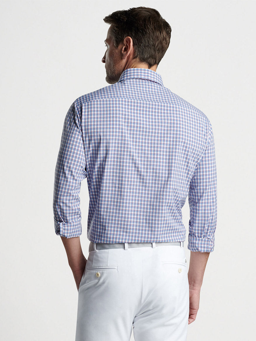 Man seen from behind wearing a Peter Millar Cole Performance Poplin Sport Shirt Regatta Blue with UPF 50+ sun protection and white pants.