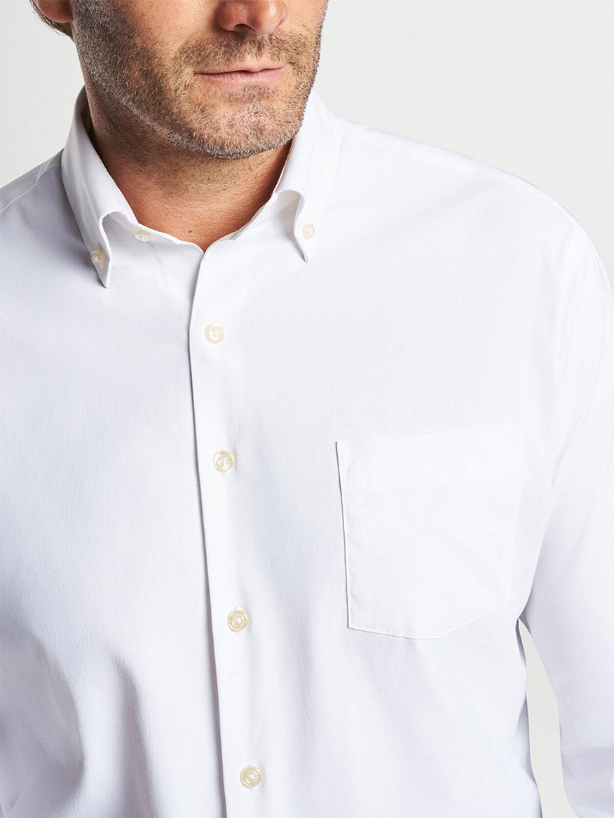 A close-up of a man wearing a Peter Millar Collins Performance Oxford Sport Shirt in White, featuring a collar and a front pocket.