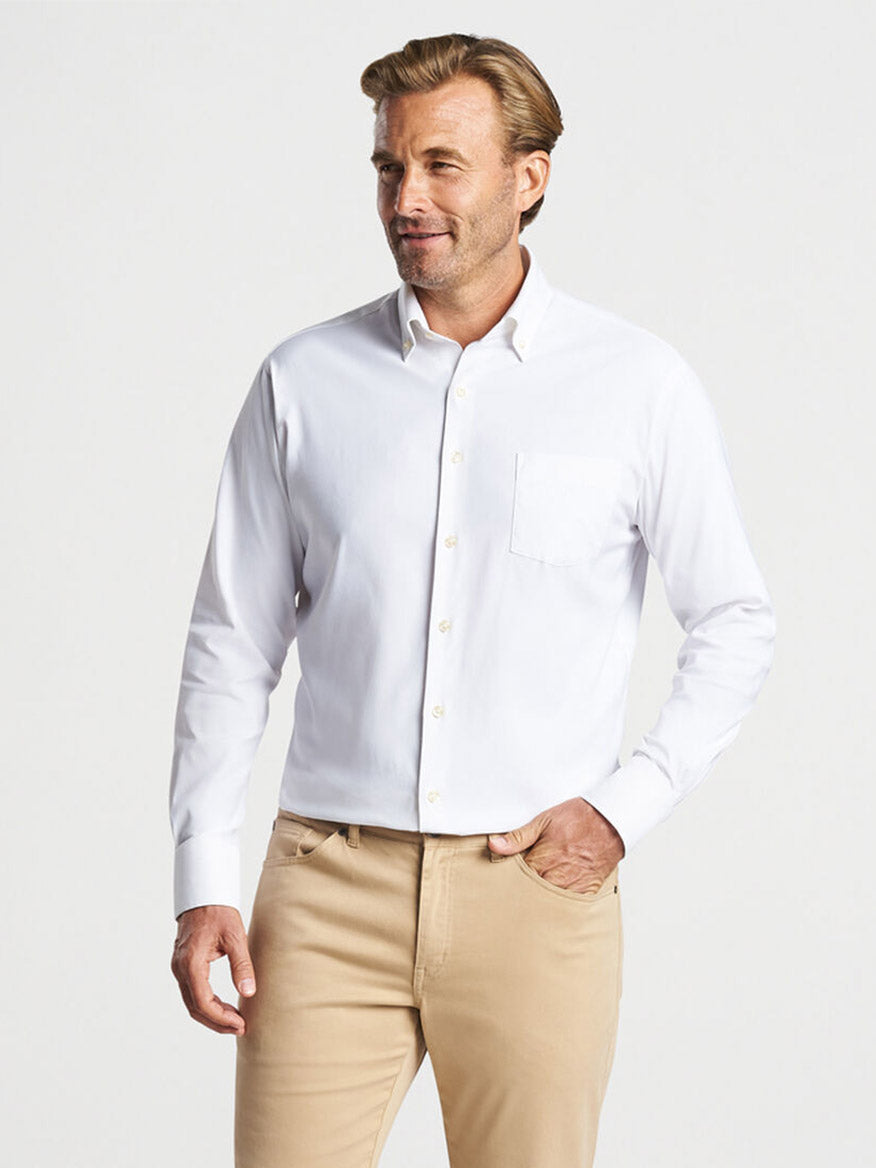 A man wearing a Peter Millar Collins Performance Oxford Sport Shirt in White and khaki pants standing with one hand in his pocket.