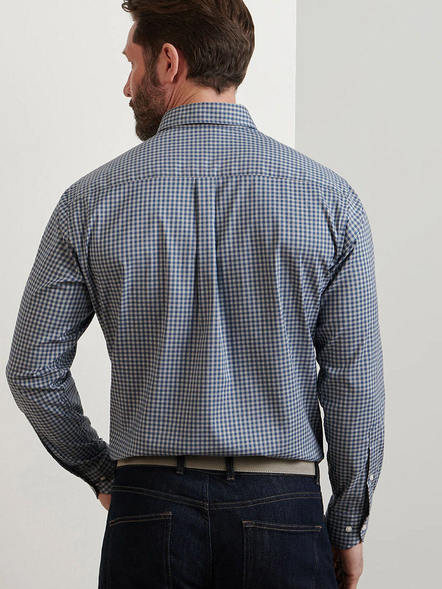 A man stands facing away in a Peter Millar Conway Crown Lite Cotton-Stretch Sport Shirt in Gale Grey, styled with dark jeans against a plain background.