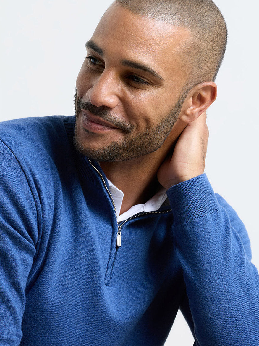 Man with short hair and trimmed beard wears a Peter Millar Coolspun Lite Cotton Quarter-Zip Sweater in Windsor Blue over a white shirt, touches the back of his neck, and smiles slightly.