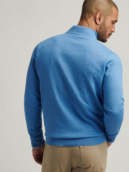 A man wearing the Peter Millar Coolspun Cotton Quarter-Zip Sweater in Blue Poppy and beige pants stands with his back to the camera, set against a plain background.