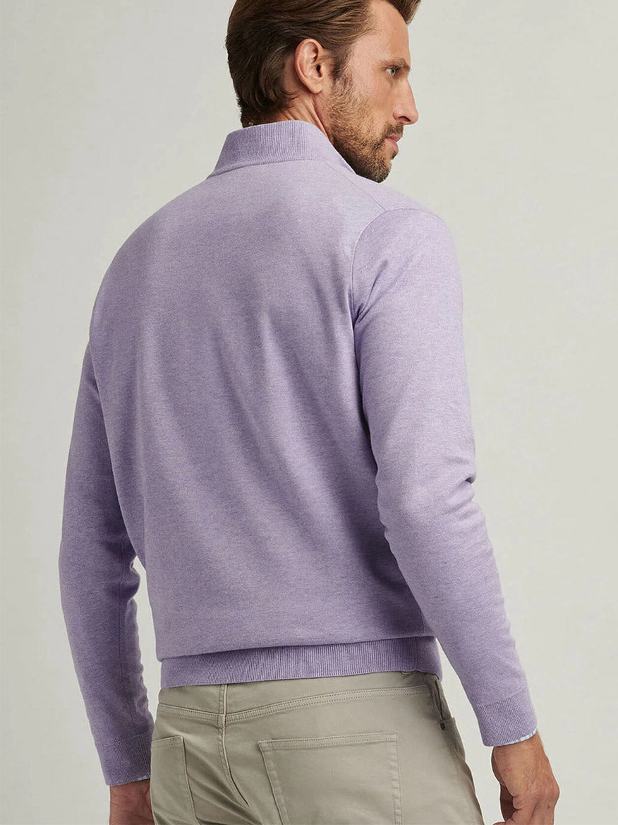 A man with short hair is turned sideways, looking over his shoulder against a neutral background, wearing beige pants and the Peter Millar Coolspun Cotton Quarter-Zip Sweater in Wildflower.