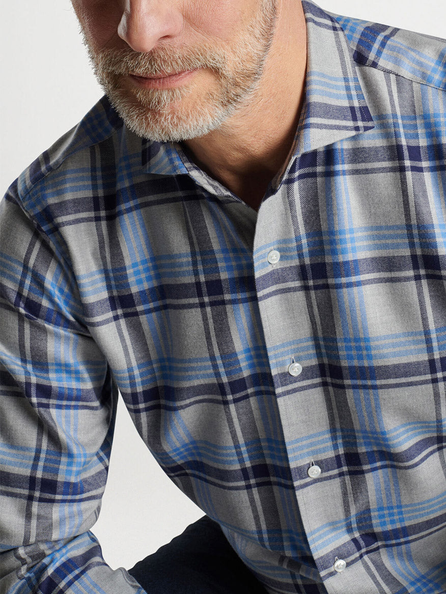 A person with a light beard wearing the Peter Millar Coulter Italian Flannel Sport Shirt in Gale Grey, featuring a tailored fit with a gray and blue plaid pattern, made from a soft cotton-blend.