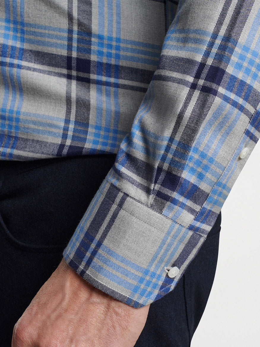 Close-up of a person's arm in the Peter Millar Coulter Italian Flannel Sport Shirt in Gale Grey, featuring buttoned cuffs that highlight its tailored fit for seasonal wear. The dark pants perfectly complement the look.