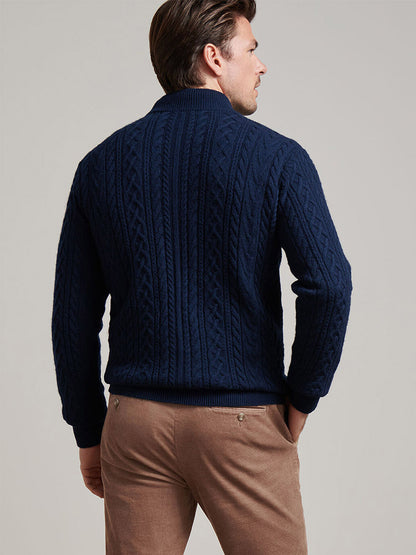A man faces away from the camera wearing the Peter Millar Crescent Ridge Cable Quarter-Zip Sweater in Navy and light brown pants, set against a plain background.