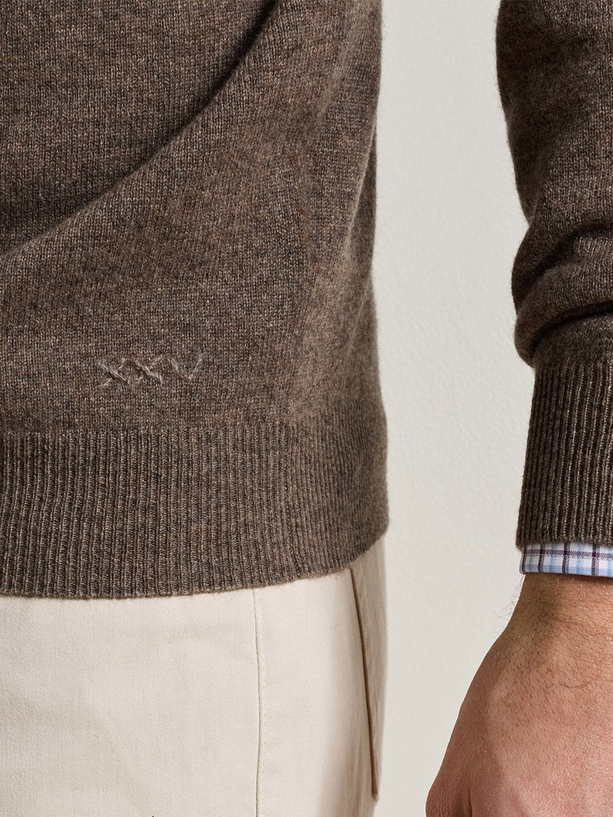 Peter Millar 25th Anniversary Cashmere Quarter-Zip Sweater in Sawgrass, a classic fit brown cashmere quarter-zip with Roman numeral XXV embroidery, worn over a light blue and white checkered shirt.