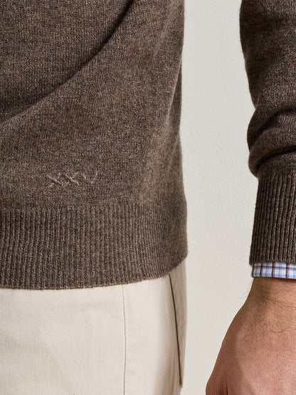 Peter Millar 25th Anniversary Cashmere Quarter-Zip Sweater in Sawgrass, a classic fit brown cashmere quarter-zip with Roman numeral XXV embroidery, worn over a light blue and white checkered shirt.