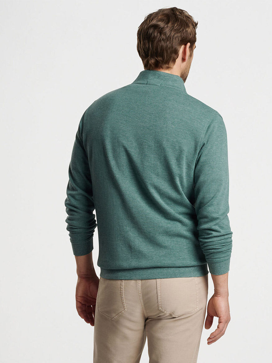 A man is standing with his back to the camera, wearing a Peter Millar Crown Comfort Pullover in Sherwood and beige pants against a plain white background.