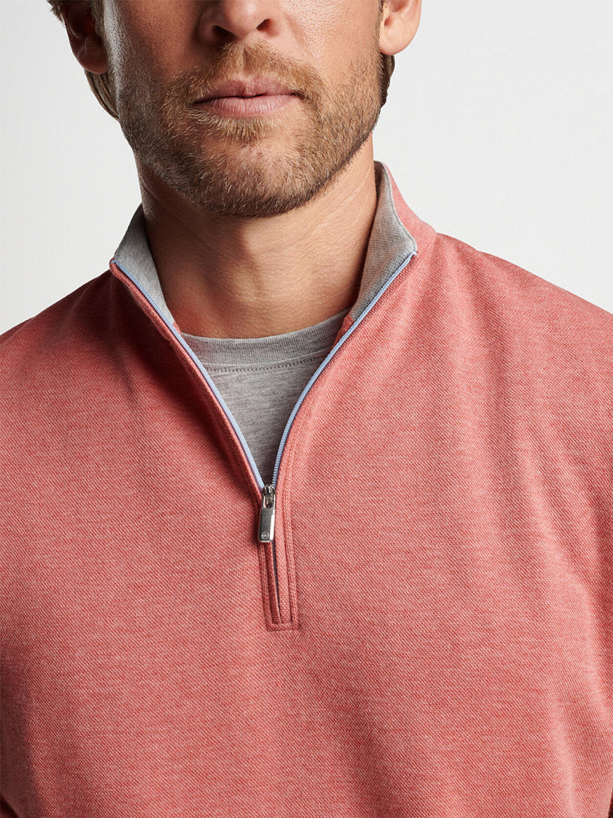 Close-up of a man wearing a Peter Millar Crown Comfort Pullover in Clay Rose with a grey t-shirt underneath, made from a versatile cotton modal blend.