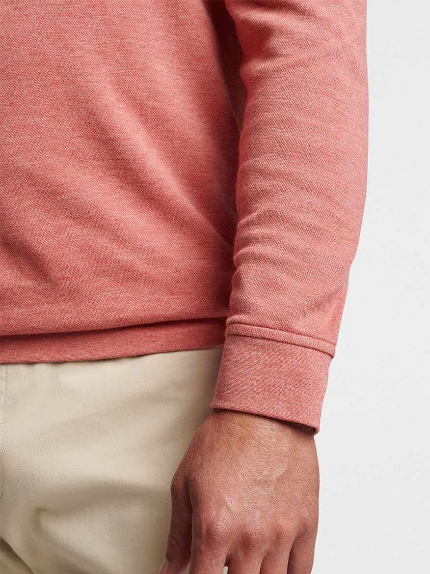 Close-up of a person wearing a Peter Millar Crown Comfort Pullover in Clay Rose and beige trousers.