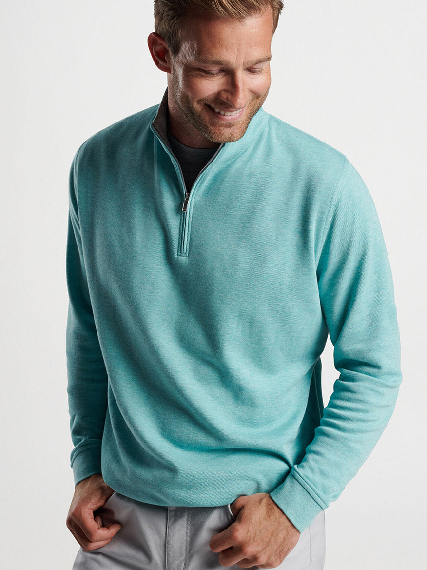 Man in a Peter Millar Crown Comfort Pullover in Cloud smiling and looking down.