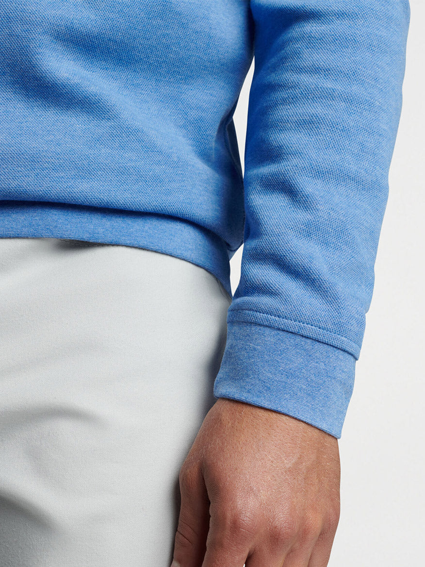 Close-up of a person wearing a Peter Millar Crown Comfort Pullover in Maritime with the sleeve rolled up, against a neutral background.