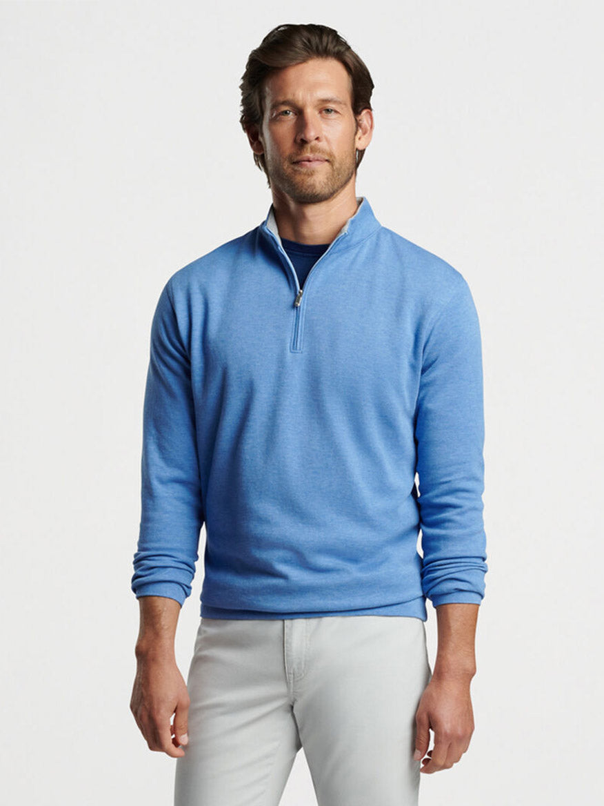 Man in a Peter Millar Crown Comfort Pullover in Maritime and light gray pants posing for a fashion shoot.