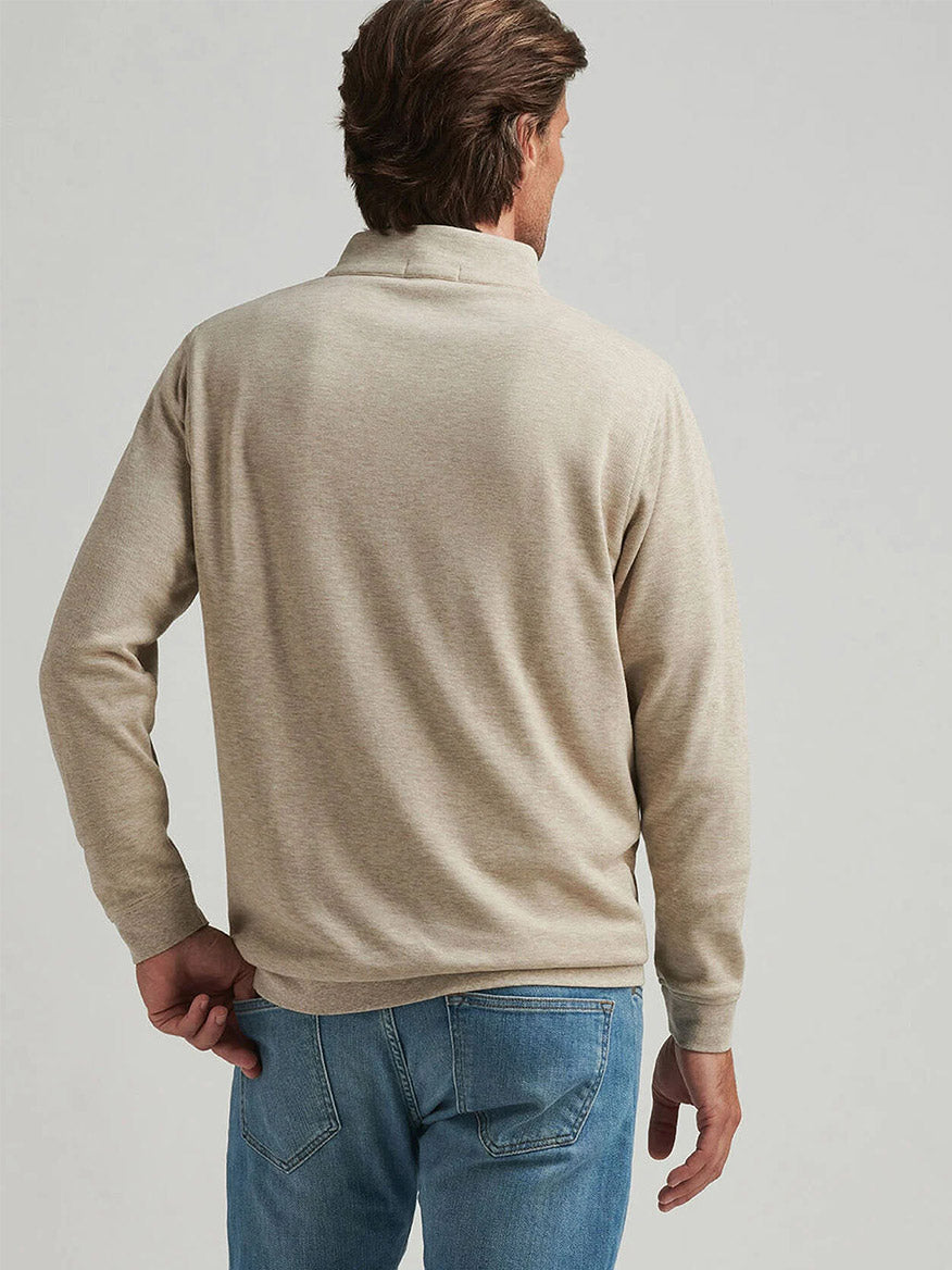 A person with brown hair is wearing a Peter Millar Crown Comfort Pullover in Stone and blue jeans, viewed from the back.