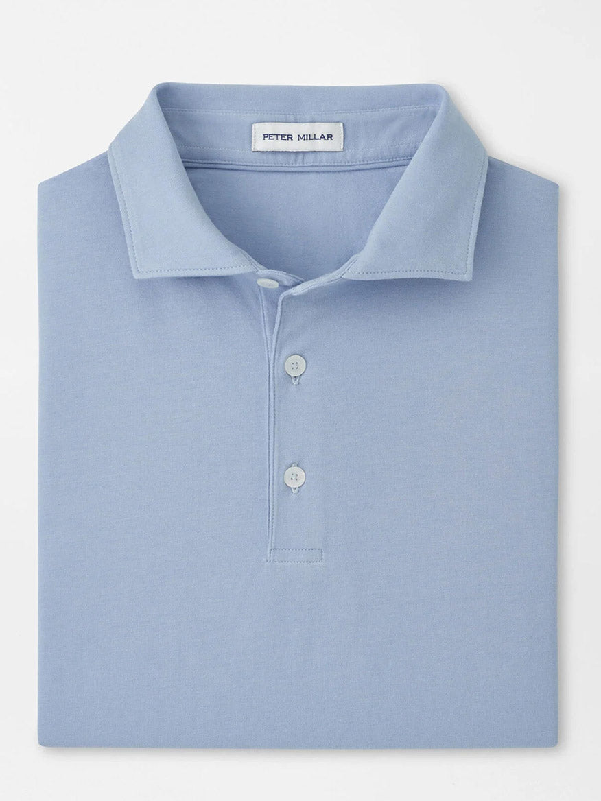 A neatly folded Peter Millar Crown Flex Cotton Polo in Cloudy Blue with a collar, three buttons, and the "Peter Millar" label inside the neckline.