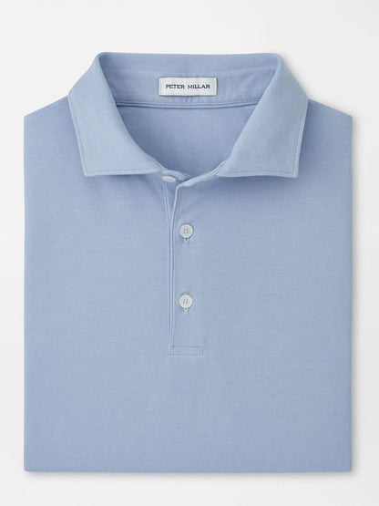 A neatly folded Peter Millar Crown Flex Cotton Polo in Cloudy Blue with a collar, three buttons, and the "Peter Millar" label inside the neckline.