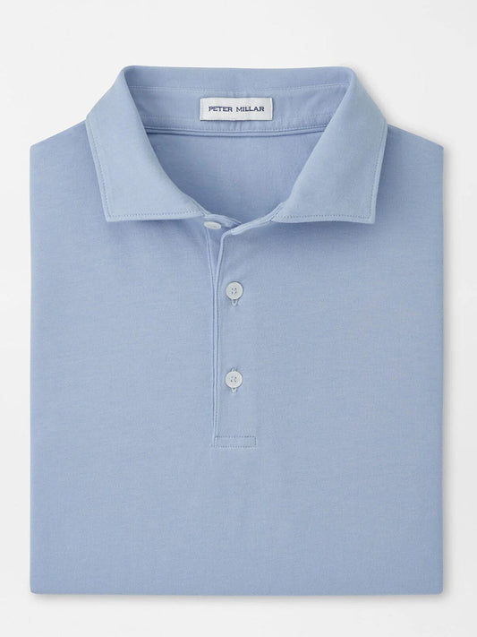 A neatly folded Peter Millar Crown Flex Cotton Polo in Cloudy Blue with a collar, three buttons, and the "Peter Millar" label inside the neckline.