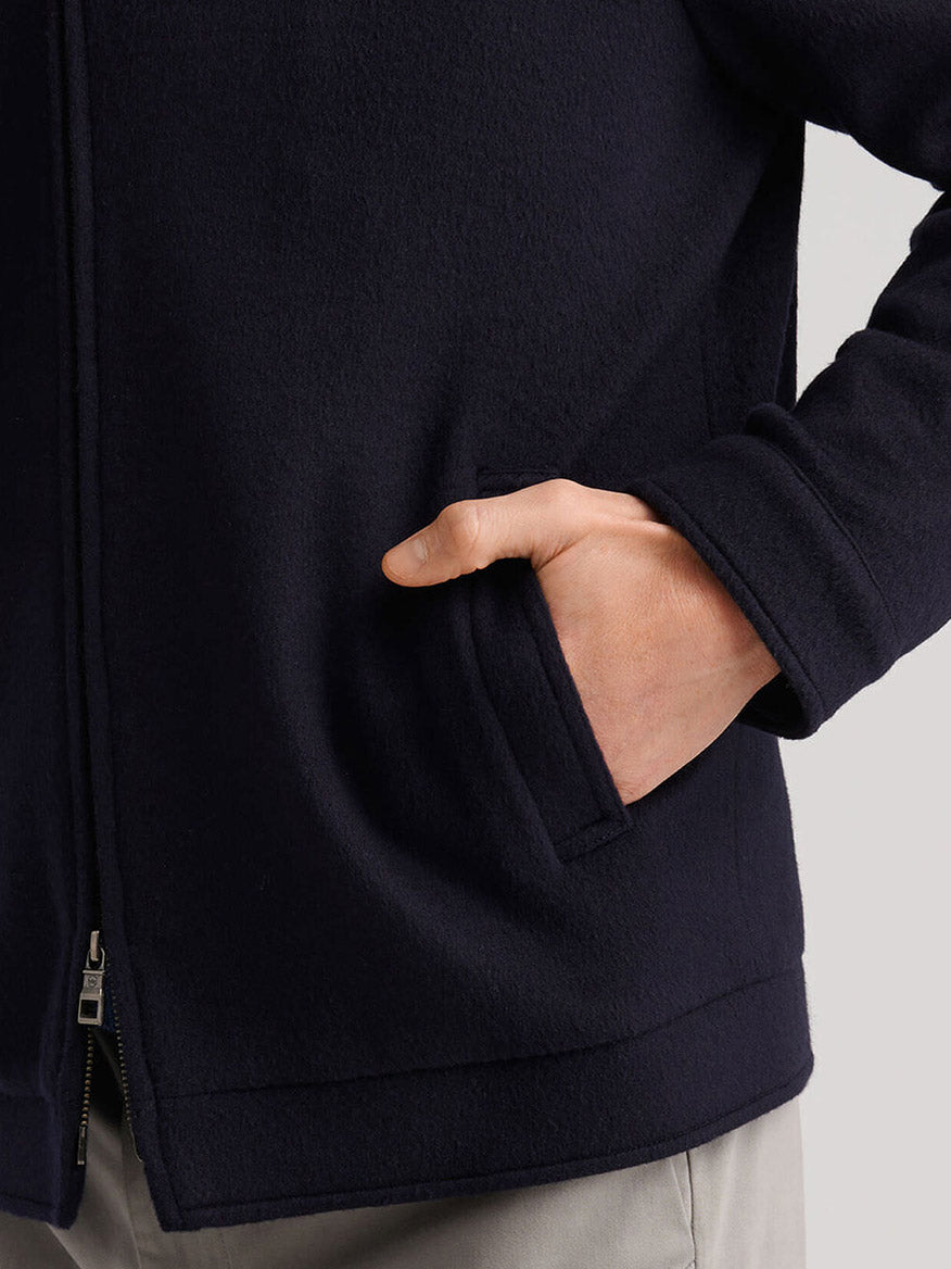 A person wearing the Peter Millar Crown Flex Merino Bomber in Navy, with one hand in the pocket and light-colored pants visible.