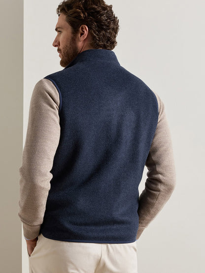 A man seen from the back wearing a Peter Millar Crown Flex Merino Vest in Atlantic Blue over a beige long-sleeved shirt.