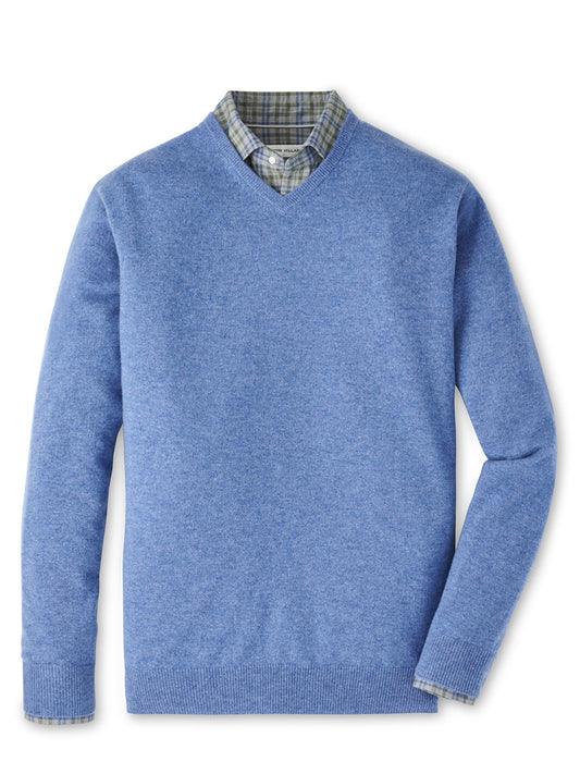 The Peter Millar Crown Heritage Cashmere V-Neck Sweater in Astral Blue is styled atop a green and gray plaid button-down shirt, both displayed flat on a white background.