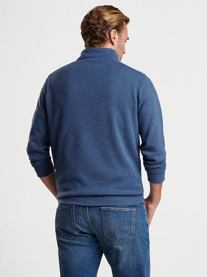 A person wearing the Peter Millar Crown Sweater Fleece Quarter-Zip in Ocean Blue and jeans is standing with their back to the camera.