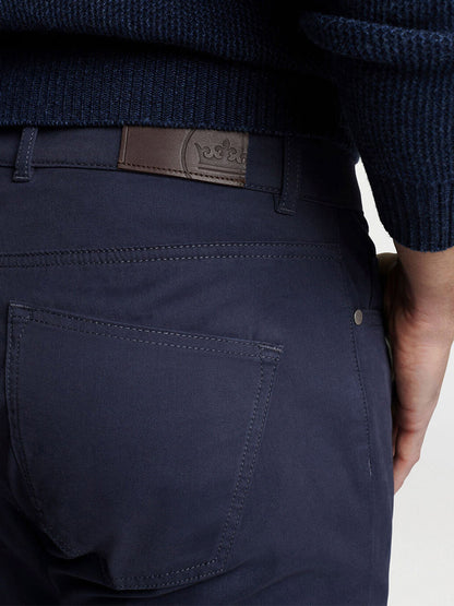 Close-up of the back pocket of the Peter Millar Delvin Twill Five-Pocket Pant in Navy, crafted from fine Italian fabric with a tailored fit and featuring a brown leather belt patch. The wearer pairs them effortlessly with a matching navy sweater.