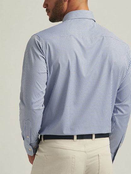 A man is seen from behind wearing a Peter Millar Derwent Performance Twill Sport Shirt in Sport Navy with beige pants.