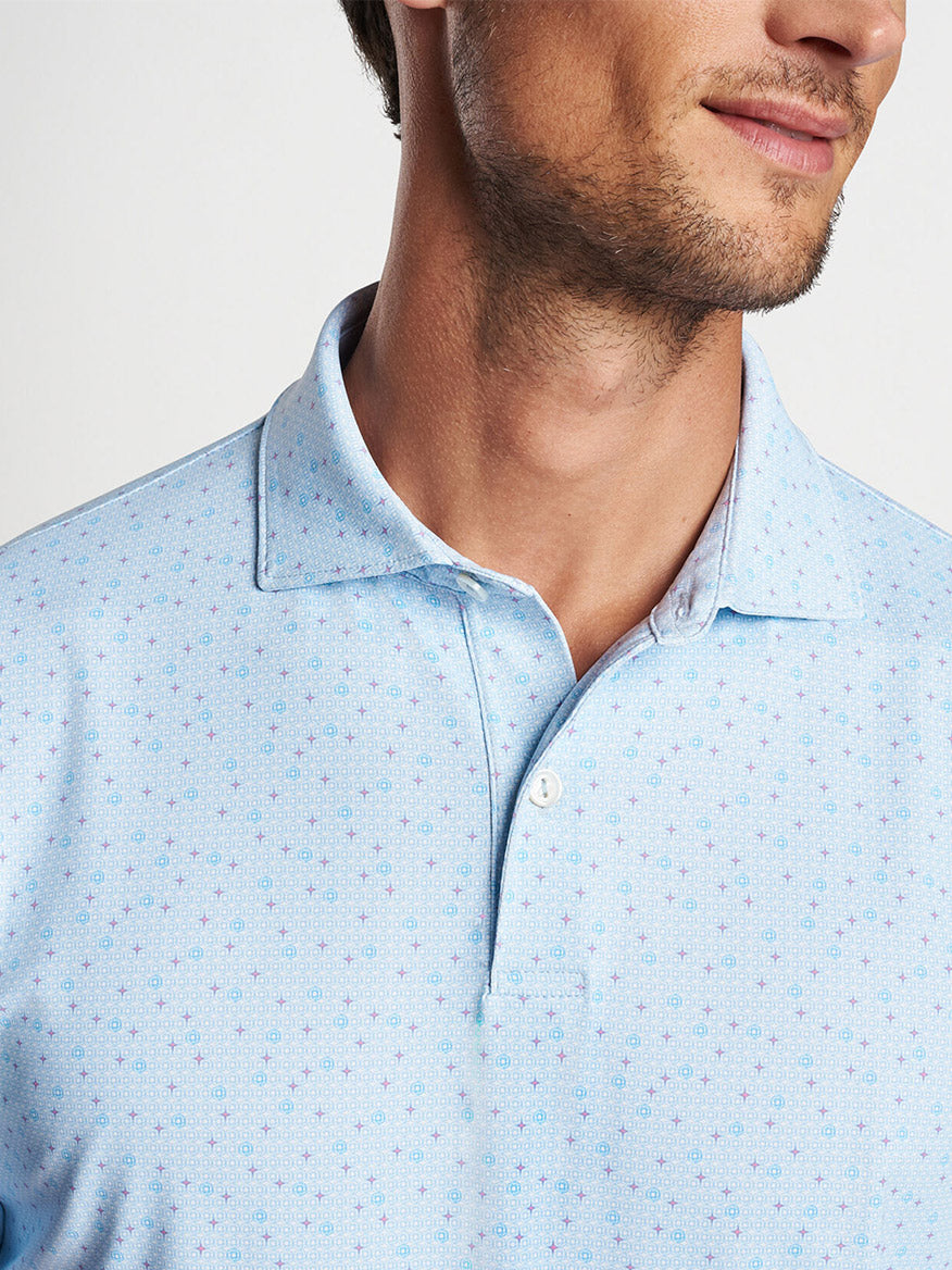 Close-up of a man wearing a light blue patterned Peter Millar Diamond In The Rough Performance Jersey Polo in Blue Frost.