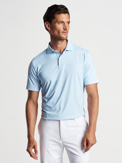 A man wearing a light blue Peter Millar Diamond In The Rough Performance Jersey Polo in Blue Frost with a pattern and white pants.