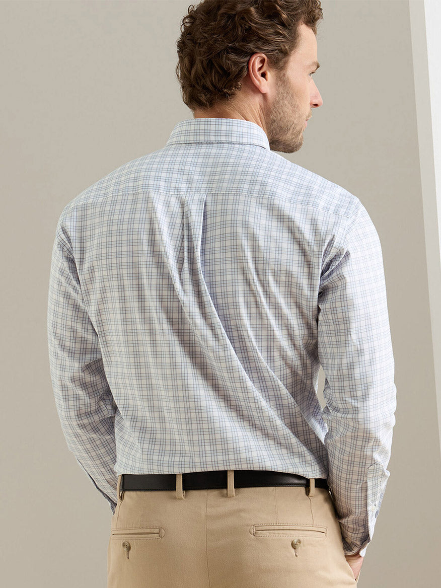 A man, seen from the back indoors, wears the Peter Millar Douglas Crown Lite Cotton-Stretch Sport Shirt in Gale Grey with beige pants.