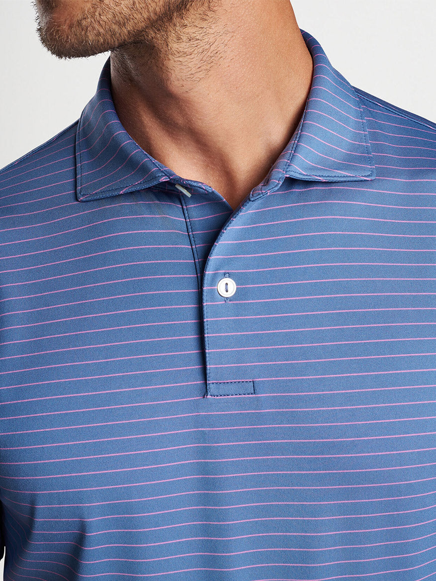 A close-up of a man wearing a Peter Millar Duet Performance Jersey Polo in Blue Pearl with the collar buttoned.