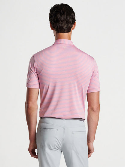 Man wearing a Peter Millar Duet Performance Jersey Polo in Spring Blossom with UPF 50+ sun protection and gray pants viewed from behind.