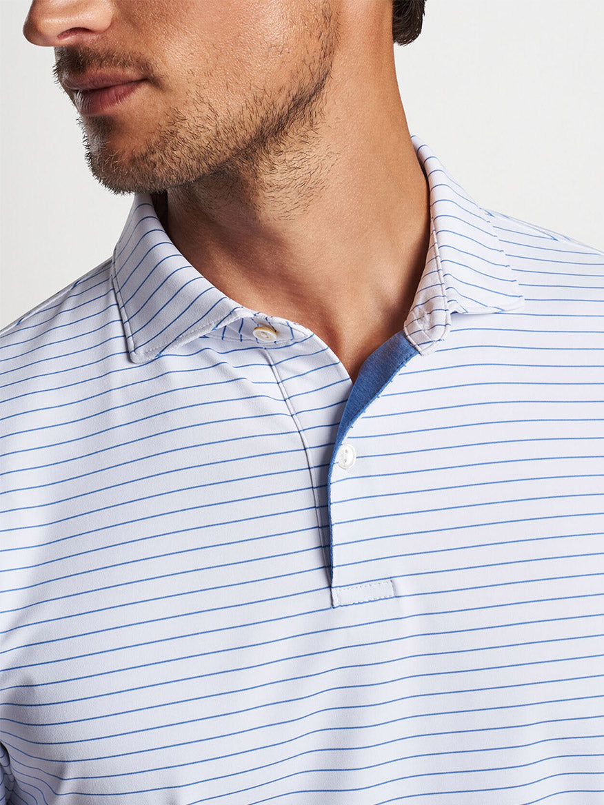 Close-up of a man in a blue and white striped Peter Millar Duet Performance Jersey Polo in White with collar details visible.