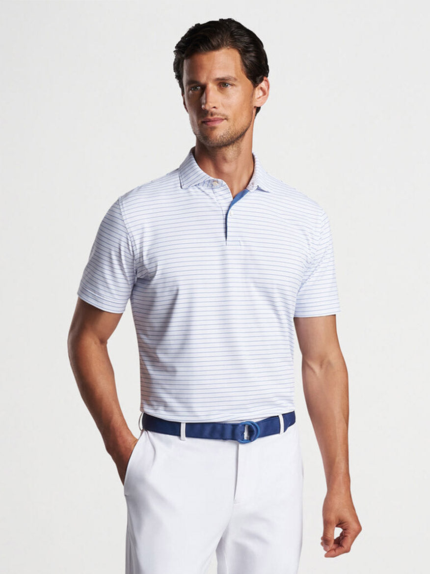 Man wearing a striped Peter Millar Duet Performance Jersey Polo in White and white pants posing for a fashion shoot.