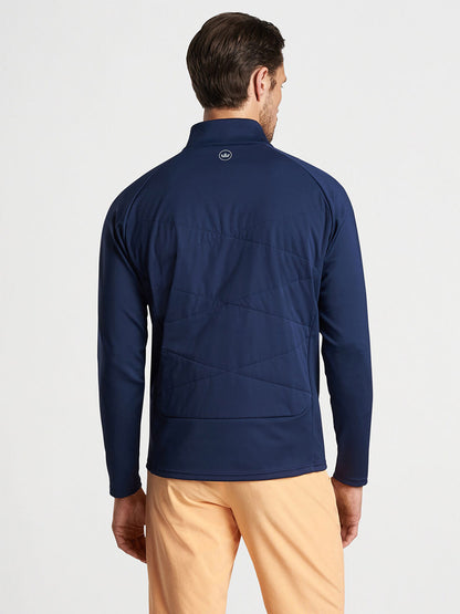 Man wearing a Peter Millar Merge Hybrid Jacket in Navy and khaki trousers seen from the back.