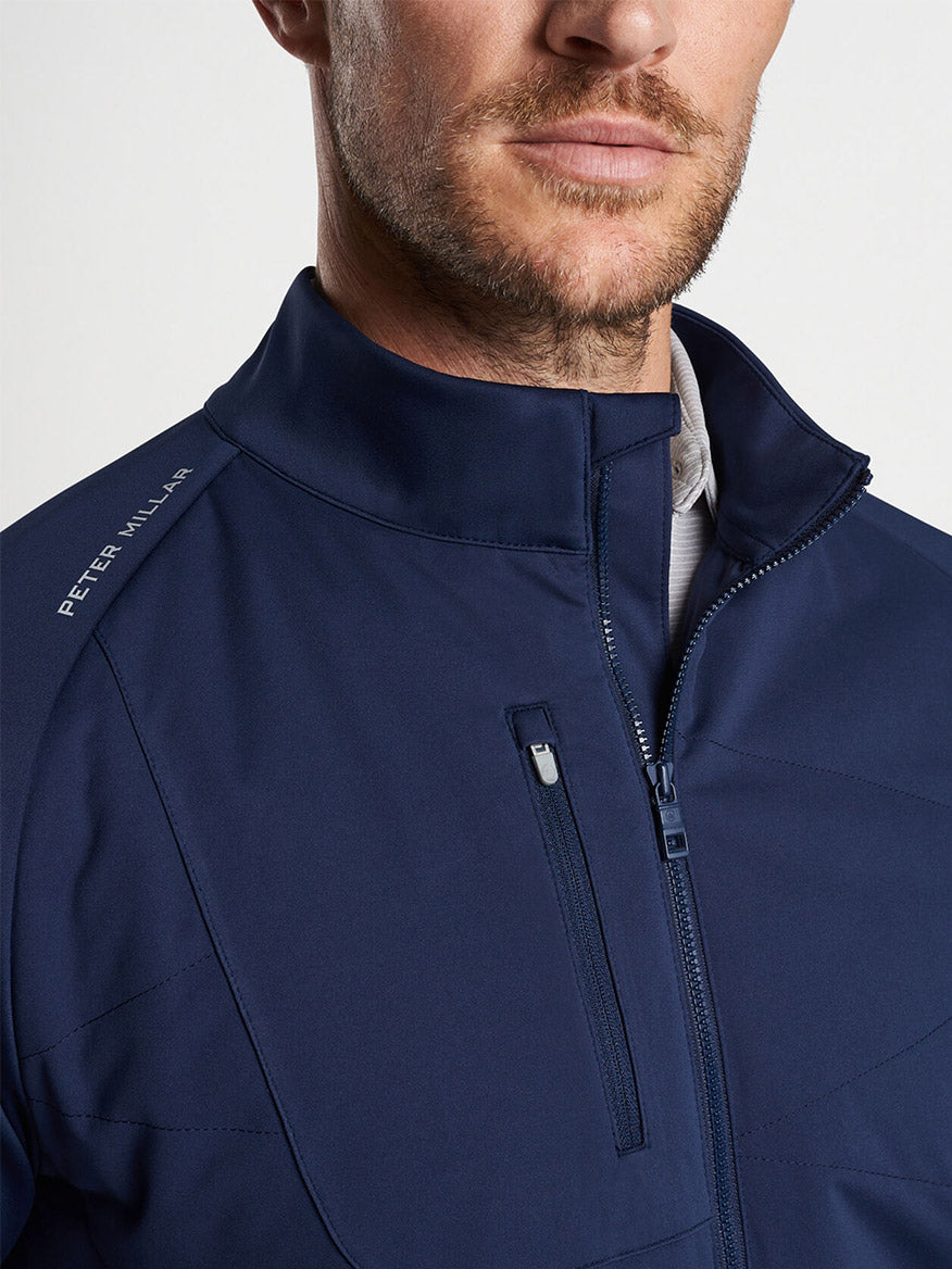 Close-up of a man wearing a Peter Millar Merge Hybrid Jacket in Navy with a zipper and a collar.