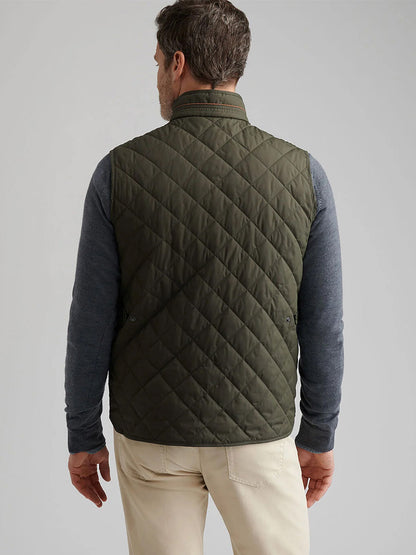 A man is seen from behind wearing the Peter Millar Essex Vest in Dark Olive over a gray long-sleeve shirt and beige pants against a plain background.