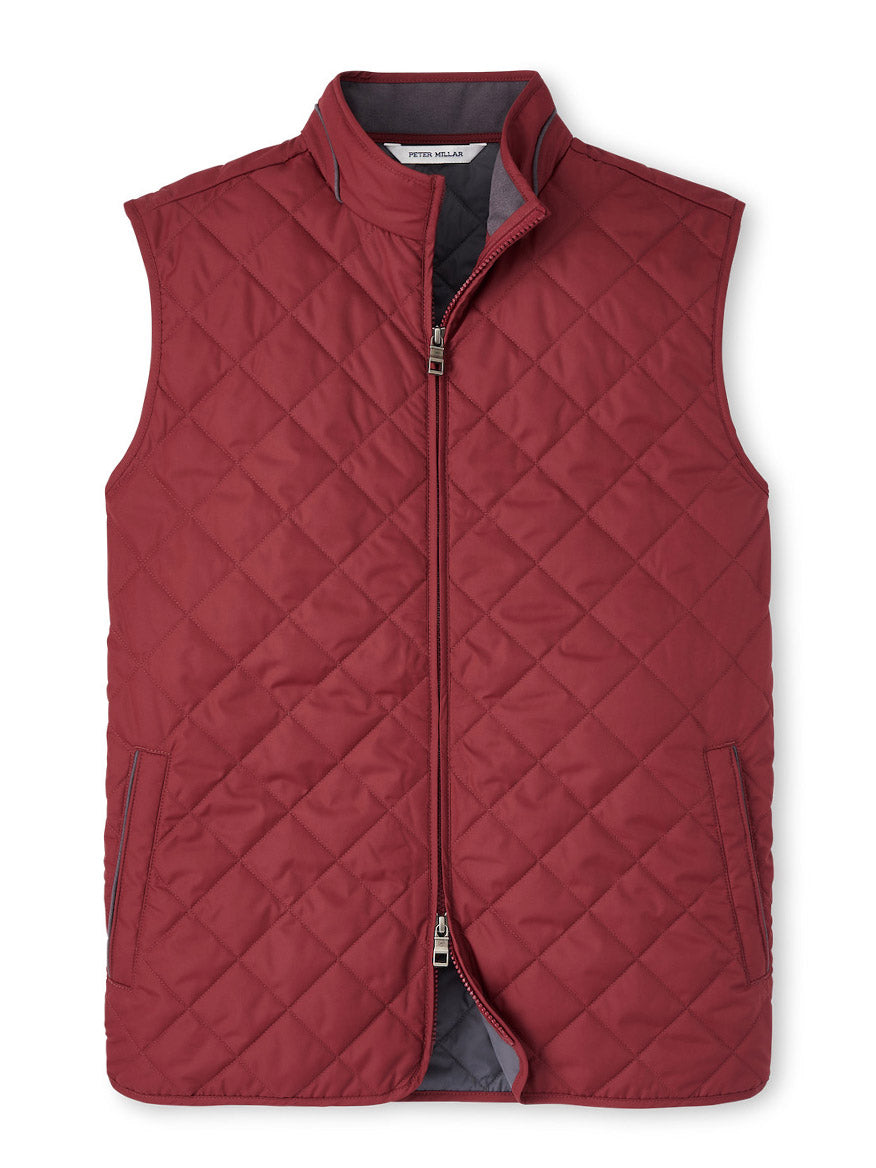 The Peter Millar Essex Vest in Celosia Red is a stylish, sleeveless quilted vest featuring a zipper front closure and two side pockets. This water-resistant and windproof piece ensures you stay comfortable in any weather condition.