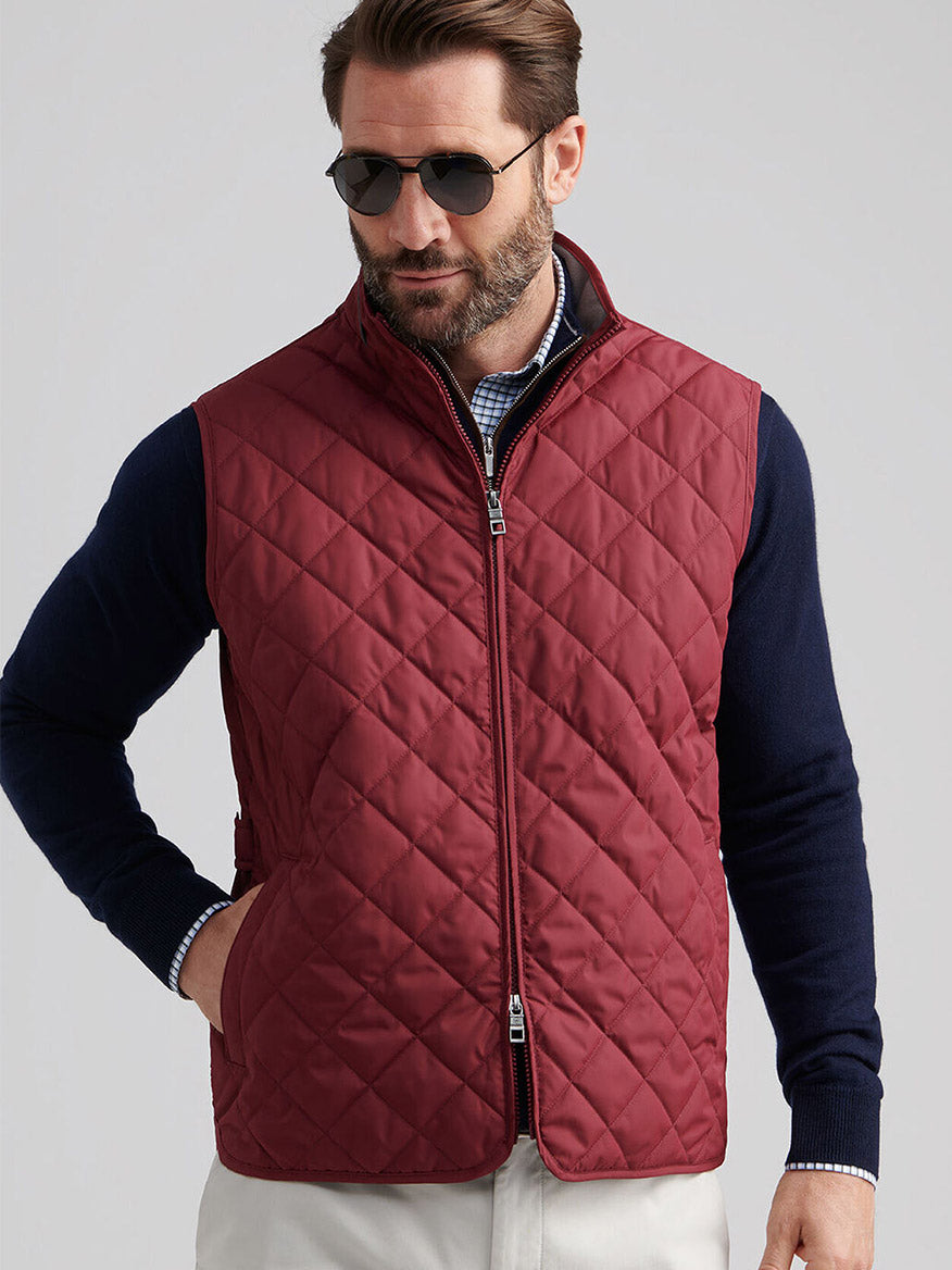 Man wearing sunglasses, a navy long-sleeve shirt, and the Peter Millar Essex Vest in Autumn Foliage with a front zipper, posing against a plain background.