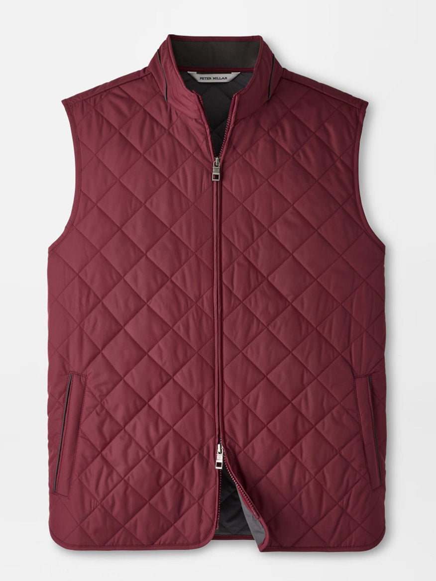 The Peter Millar Essex Vest in Bordeaux is a maroon quilted vest featuring a front zipper, two zippered side pockets, and a stand collar, designed as a stylish windproof layer and shown on a plain white background.
