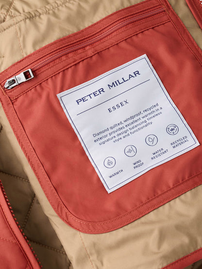 Close-up of the interior of a Peter Millar Essex Vest in Burnt Orange, featuring a label that highlights its warmth, windproof design, water resistance, and use of recycled materials.