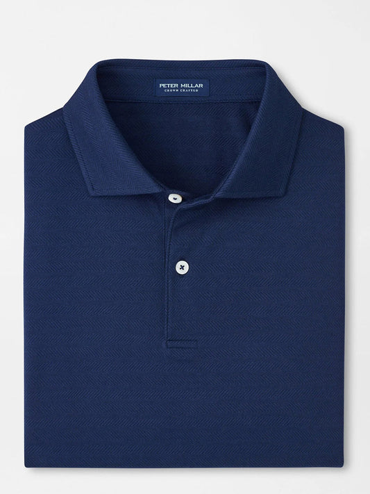 A neatly folded Peter Millar Excursionist Flex Herringbone Knit Polo in Navy features a collared design, two white buttons, and the brand label inside the neckline, crafted from soft cotton jersey knit for comfort.