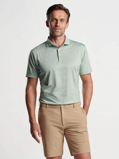 Peter Millar, a man in a green polo shirt showcasing refined casual style with the Peter Millar Excursionist Flex Short-Sleeve Polo in Sage Fog.