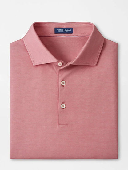 A neatly folded Peter Millar Excursionist Flex Polo in Faded Scarlet with a collar, three buttons, an inside neck label, and crafted from soft cotton jersey knit.