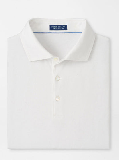 The Peter Millar Excursionist Flex Polo in White is a folded, cotton-based jersey knit polo with a collar and three buttons. A blue label inside the collar displays "Peter Millar.